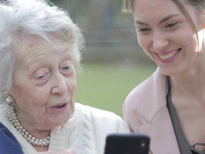 Woman and elder woman looking at phone communicating